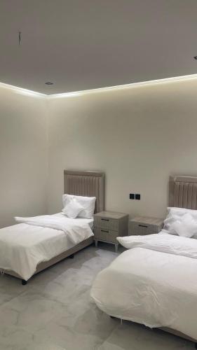 two beds in a room with white walls at 2Bedrooms Family Apartment S19 in Al Kharj