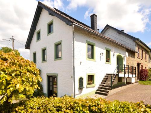 ビュートゲンバッハにあるHoliday home in Butgenbach near the Lakeの緑色のドアと階段のある古い白い家