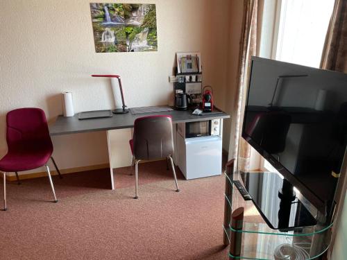 a room with a desk with two chairs and a television at Ruhige Zimmer im Grünen und Studio im Naherholungsgebiet in Sigigen