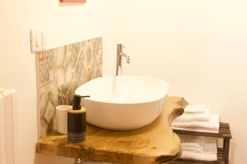 a bathroom with a white bowl sink on a wooden counter at Rebeccu Arte e Ospitalità - Ostello in Rebeccu