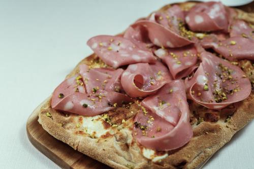 a pizza with meat on top on a cutting board at Hotel dP Olbia - Sardinia in Olbia