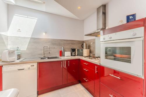 a kitchen with red cabinets and a sink at La Maison de Retz - 400m centre - Jardin in Bourgneuf-en-Retz