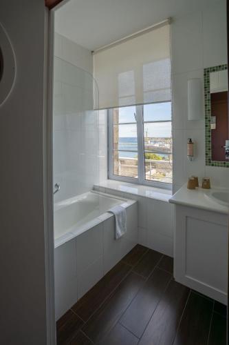 a bathroom with a tub and a sink and a window at Hotel Mercure Roscoff Bord De Mer in Roscoff