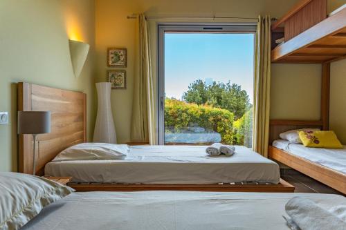 Dos camas en una habitación con ventana. en Villa Pina, en Sainte-Lucie de Porto-Vecchio