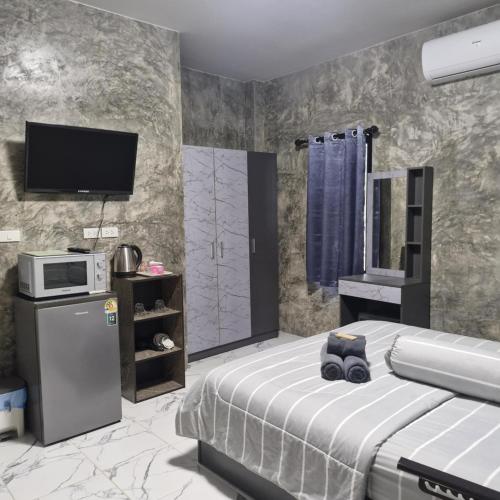 a bedroom with a bed and a tv on the wall at Baan Raweewan Resort in Ban Phu Yai