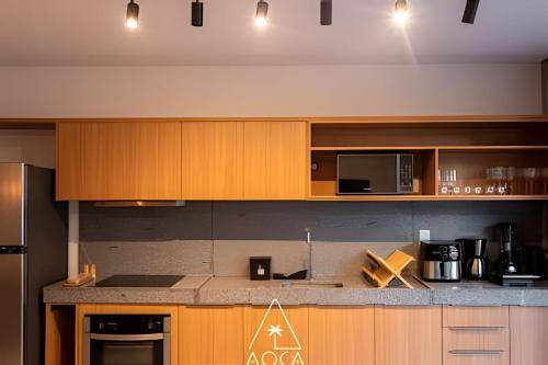 a kitchen with wooden cabinets and a counter top at Villa Naluri - Seu Refúgio a 50 metros da praia em Japaratinga in Japaratinga