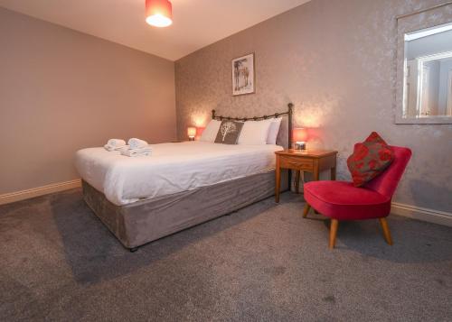 a bedroom with a large bed and a red chair at The Queens Hotel & Victoria Cloisters Apartments in York