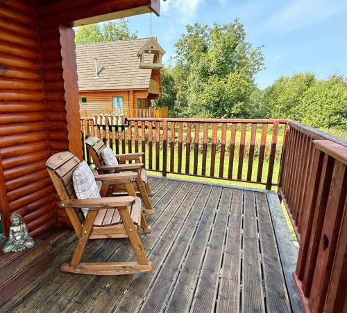 a wooden deck with two chairs on a cabin at Cois na hÉirne - Log Cabin I Lake View I Hot Tub in Belturbet