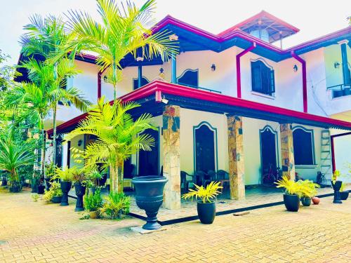 a house with palm trees in front of it at New Ridmi Villa Hiriketiya in Dickwella