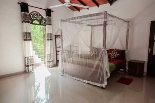 a bedroom with a bed with a canopy at New Ridmi Villa Hiriketiya in Dickwella