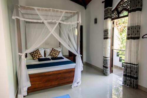 ディックウェラにあるNew Ridmi Villa Hiriketiyaの天蓋付きベッドのある寝室