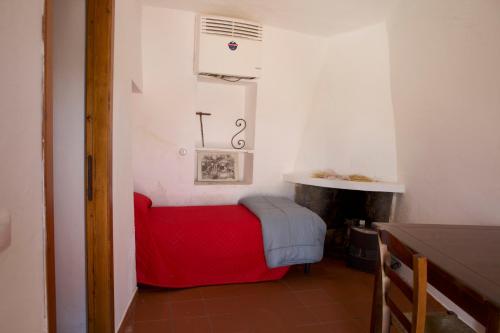 a small bedroom with a red bed and a fireplace at Rebeccu Arte e Ospitalità - Ostello in Rebeccu
