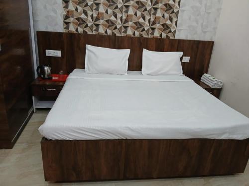 a bed with a wooden headboard and white sheets at Shree shyam kunj home stay in Vrindāvan