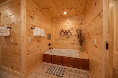 a bathroom with a tub in a wooden wall at Always Dreaming by American Patriot Getaways in Hatchertown