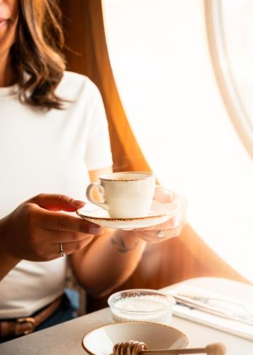 a woman holding a cup of coffee on a table at Hotel Le Grand Pavois in Fécamp
