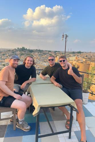 a group of people sitting at a table on a roof at Hostel Peace & Love Home Stay in Jaisalmer