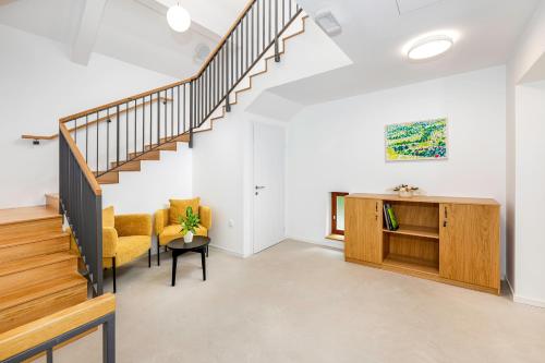 a living room with a staircase and a yellow chair at Rooms & Apartments Podsreda Castle in Podsreda