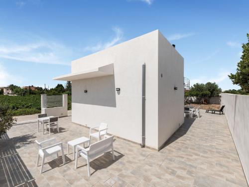 a white building with chairs and tables on a patio at Modern Villa Near Trapani in Locogrande