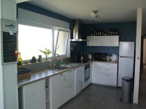a kitchen with white cabinets and a blue wall at Holiday Home in Audresselles by Seacoast in Audinghen