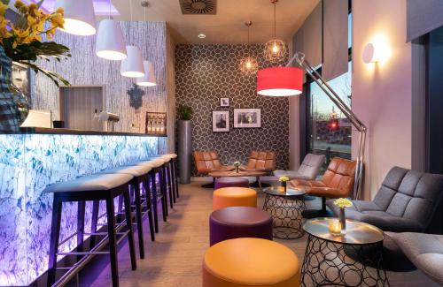 a bar withools and tables in a restaurant at Leonardo Hotel Munich City East in Munich