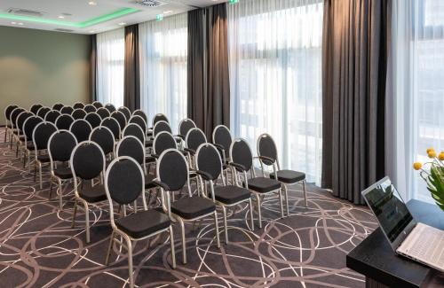 a conference room with a row of chairs and windows at Leonardo Hotel Munich City East in Munich