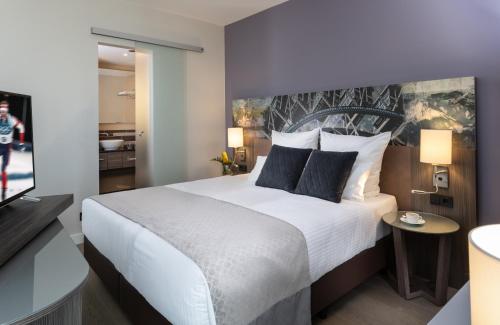 a bedroom with a large white bed with blue pillows at Leonardo Hotel Munich City East in Munich
