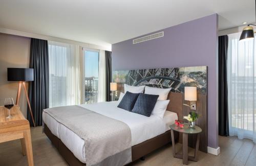 a bedroom with a large bed and a large window at Leonardo Hotel Munich City East in Munich