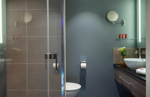 a bathroom with a shower with a toilet and a sink at Leonardo Hotel Munich City East in Munich