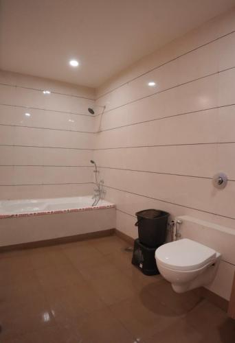 a bathroom with a toilet and a bath tub at The Moris palace hotel in Rajkot