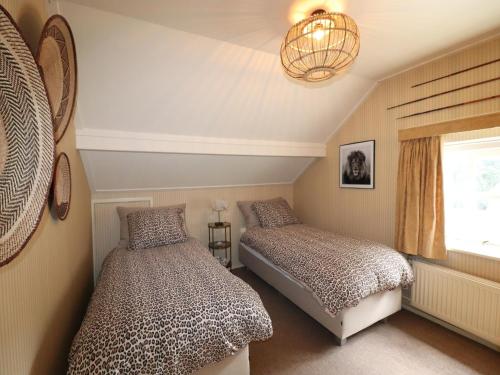 a bedroom with two beds and a chandelier at Villa in Ommen with Private Pond in Rheezerveen