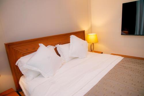 a bedroom with a white bed with white pillows at Maison Luxe Apartments in Nkunjila