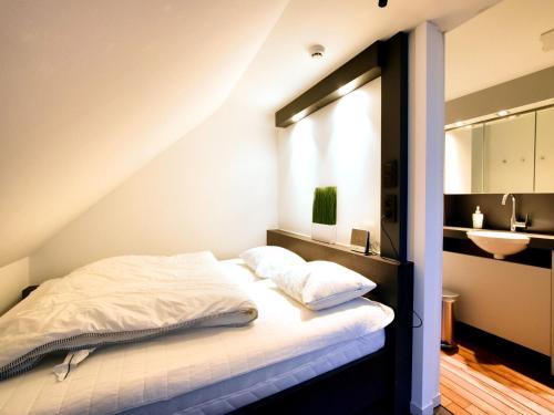 a bed with white sheets and a sink in a room at Manor house studio in Robertville in Robertville
