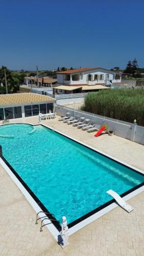 a large swimming pool with blue water in front of a building at Villa acqua e sale in Santa Maria Del Focallo
