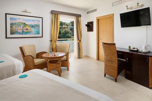 a hotel room with a bed and a table and chairs at Hotel Apartamentos Cala Santanyi in Cala Santanyi