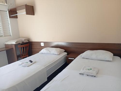 two beds in a hotel room with white sheets at Hotel Castro Alves Norte in Marília