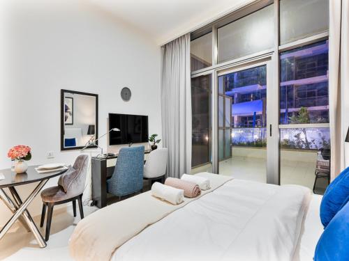 una camera con un grande letto bianco e una scrivania con sedia di Savis Homes - Furnished Spacious Studio in Golf Promenade 2A by Damac Hills a Dubai
