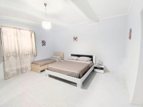 a white bedroom with two beds and a window at Dimora dello Stretto Intero Appartamento 4 posti Self Check-in Cucina Lavatrice Vicino Policlinico in Messina