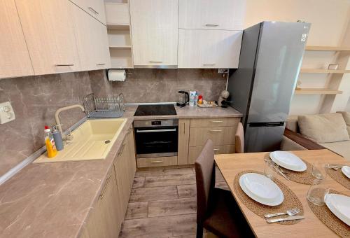 une petite cuisine avec un évier et un réfrigérateur dans l'établissement Уютен двустаен Гранд мол, à Varna