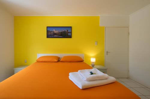 a bedroom with an orange bed with a yellow wall at The Green Turtle Eco Lodge in Willemstad