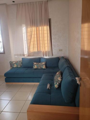 - un canapé bleu dans le salon doté d'une fenêtre dans l'établissement Sea View Apartment, à Sidi Bouqnadel