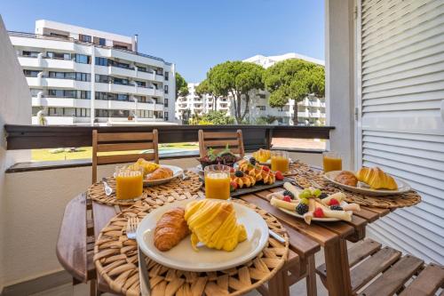 a table with breakfast food on a balcony at Vilamoura Retreat with Pool & Balcony by HostWise in Quarteira