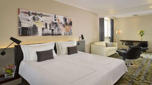 a hotel room with a large white bed and a desk at Park Plaza Victoria Amsterdam in Amsterdam