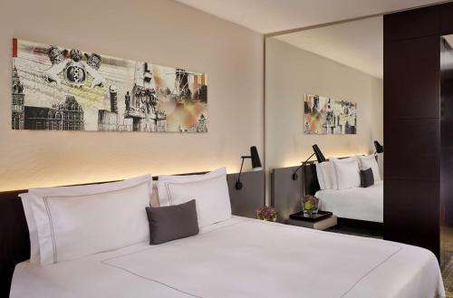 a bedroom with a large white bed and a mirror at Park Plaza Victoria Amsterdam in Amsterdam