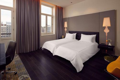 a bedroom with a large white bed and two windows at Park Plaza Victoria Amsterdam in Amsterdam
