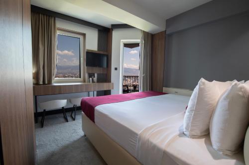 a hotel room with a bed and a desk and window at View Inn Boutique Hotel in Skopje