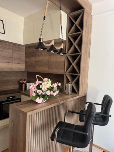 a kitchen with black chairs and a counter with flowers at Apartman Golden Crown in Vranje