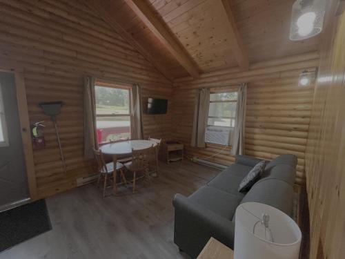 a living room with a couch and a table at Adventures East Cottages and Campground in Baddeck Inlet