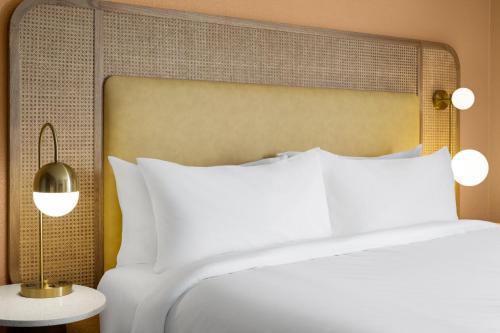 a bed with white pillows and a large headboard at voco The Shelby - Myrtle Beach by IHG in Myrtle Beach
