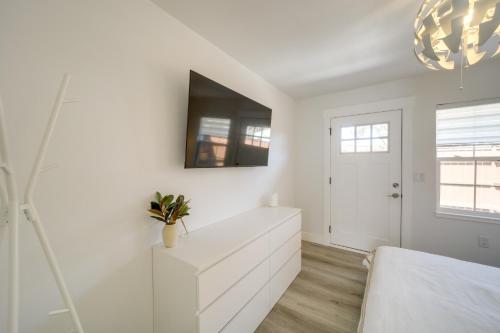 a white bedroom with a white dresser and a tv at Walk to Water Soap Lake Studio with Patio! in Soap Lake