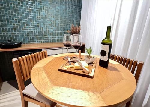 a wooden table with a bottle of wine and glasses at RefugioBacutia- Prédio FRENTE MAR Bacutia- 6 pessoas- 3 Quartos com AR sendo 1 suite - varanda- sala de estar e jantar Ampla -Piscina e Sauna no Prédio in Guarapari